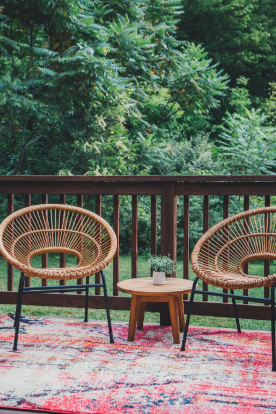 Deck with wooden railing and chairs looking into green trees